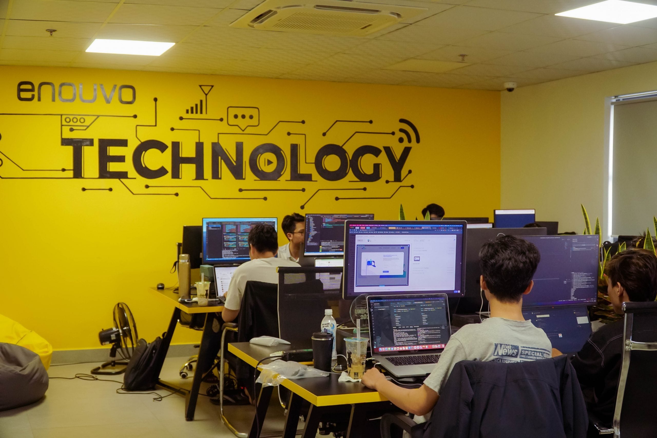 Enouvo engineers working beneath the office technology wall